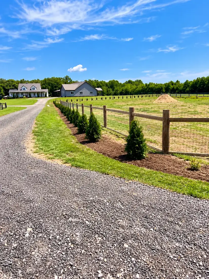 Rail and wire fence along a gravel drive to a farmhouse