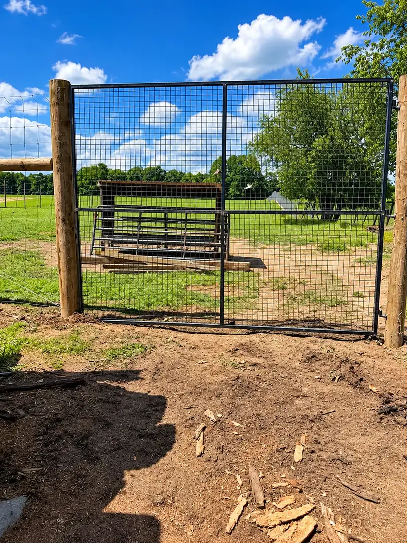 Heavy wire gate between large posts at a pasture entrance