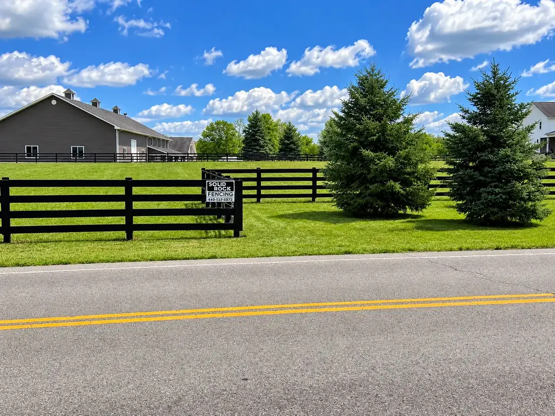 Black four-board fence along a country road