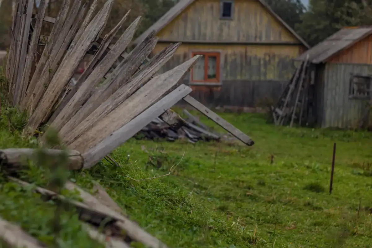 A collapsed old wood fence beside a barn